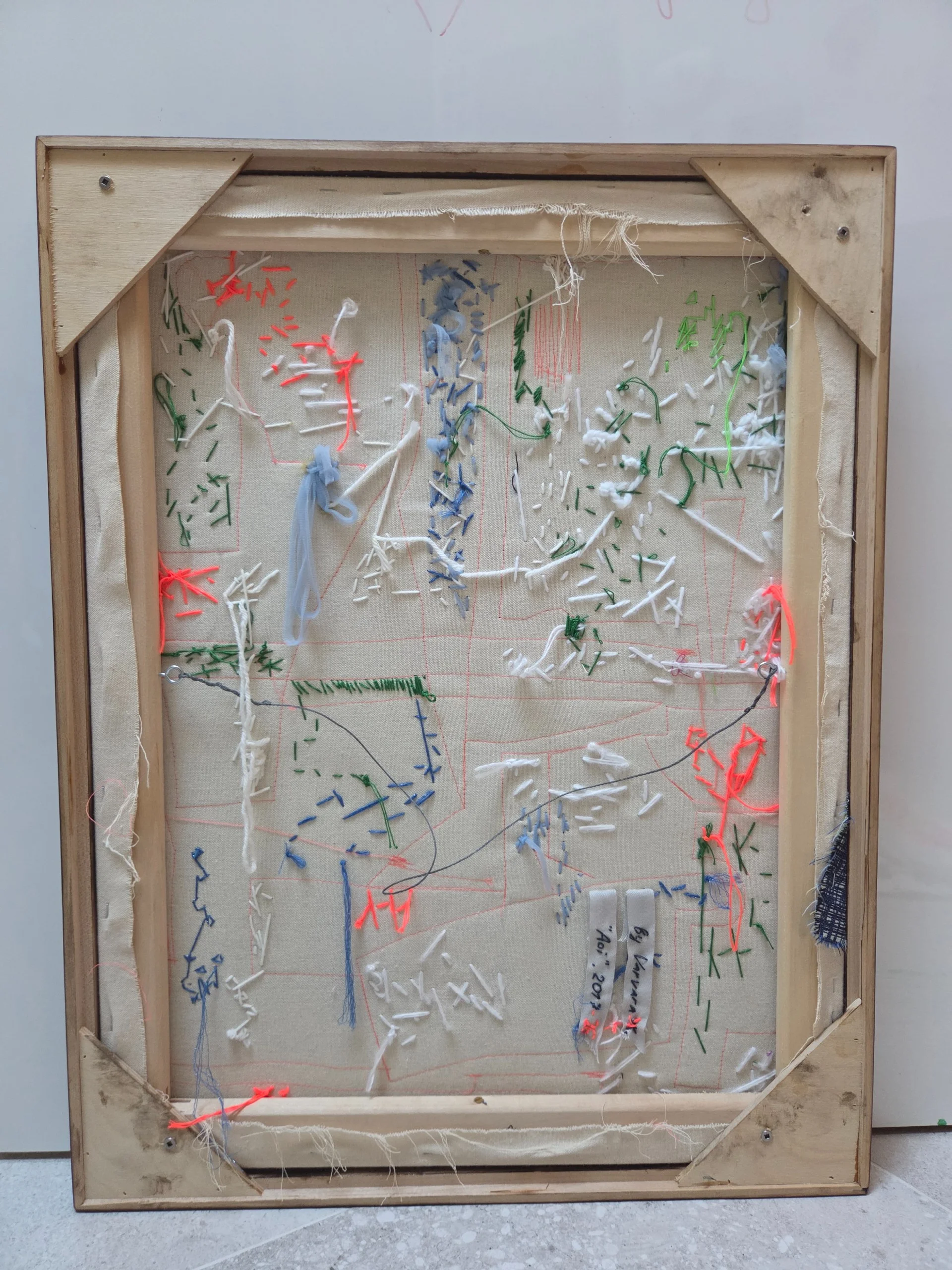 Reverse of the artwork showing a raw wooden frame and loose threads