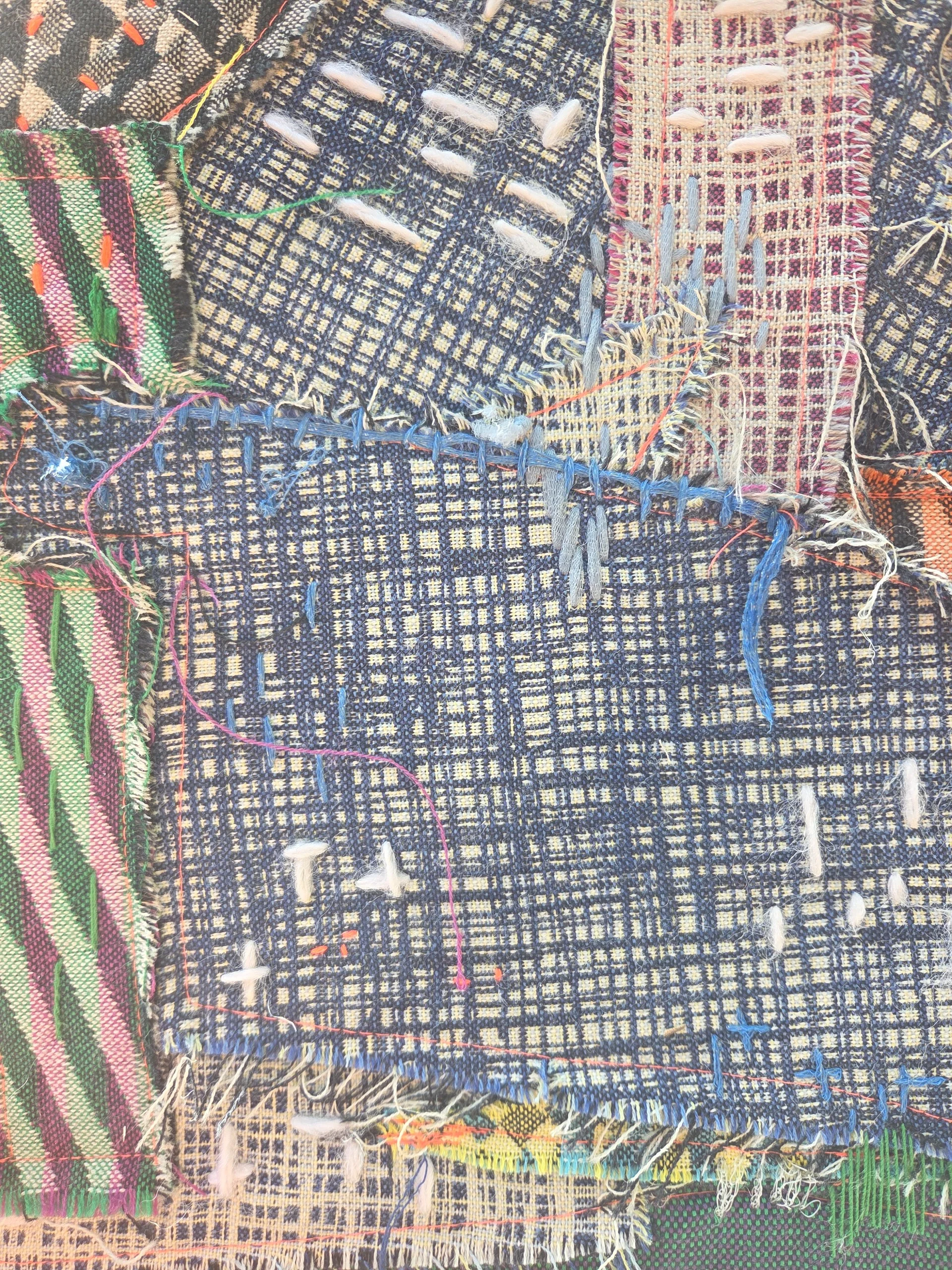Close-up of a dense navy woven panel crossed by coloured stitching
