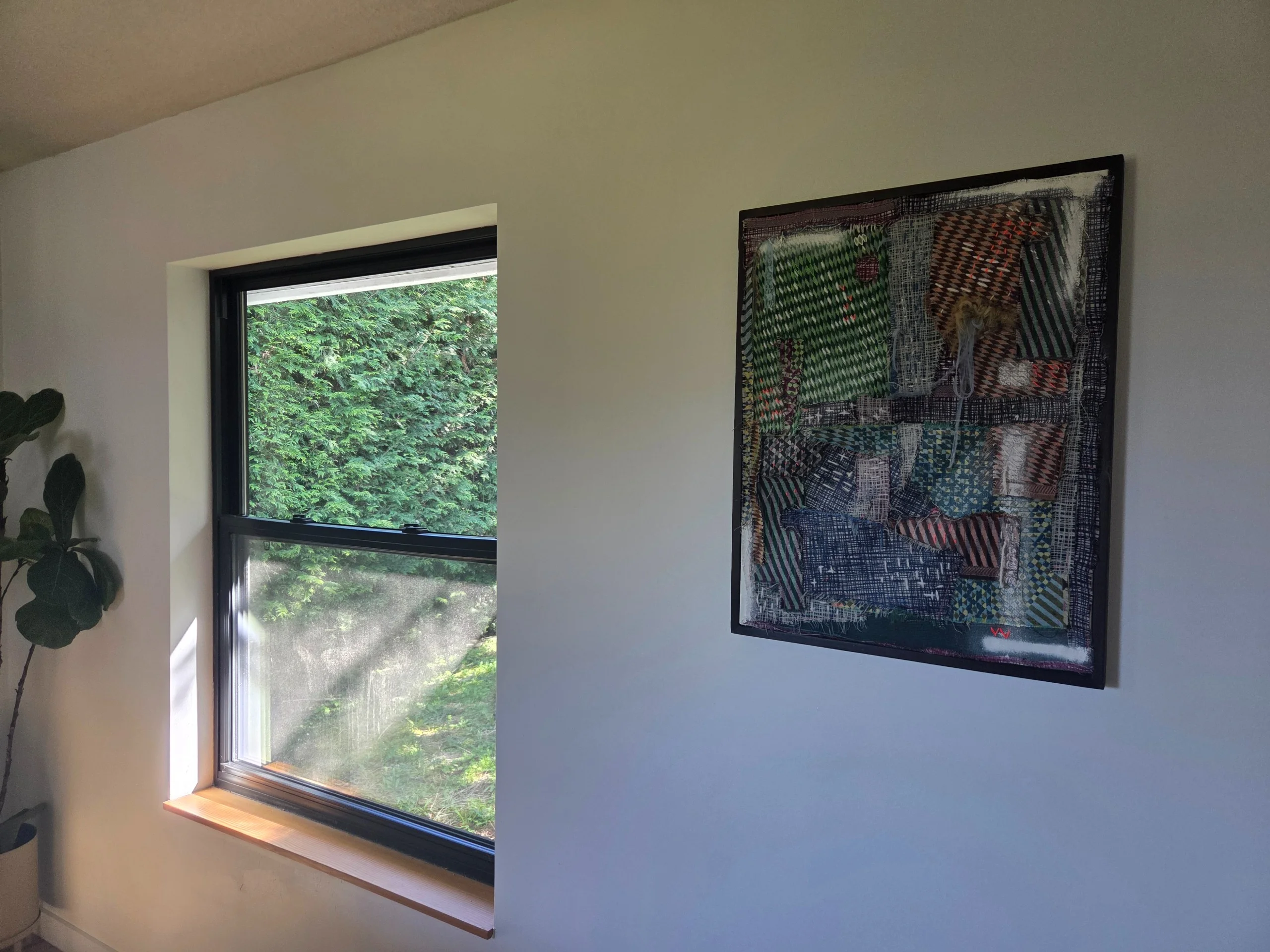 Aoi hung beside a window with daylight and greenery beyond